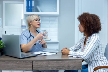 At the doctors. Curly-haired young womna having an appotimnet with a doctor