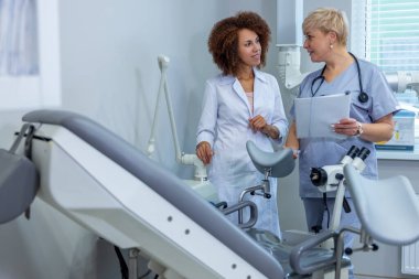 Doctors at work. Two doctors standing near gynecological chair and discussing the diagnosis