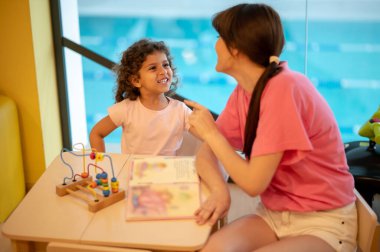 Play room. Young dark-haired woman playing with her kid in a play room