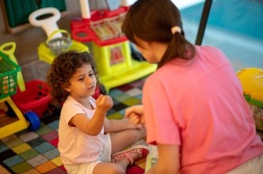 Play room. Young dark-haired woman playing with her kid in a play room