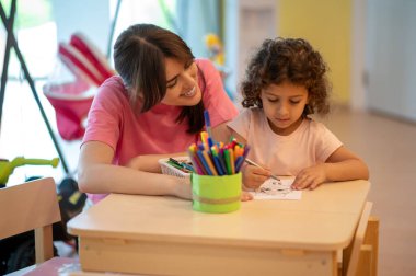 Arts. Mom and her daughter spending time in a play room drawing