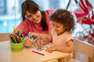 Arts. Mom and her daughter spending time in a play room drawing