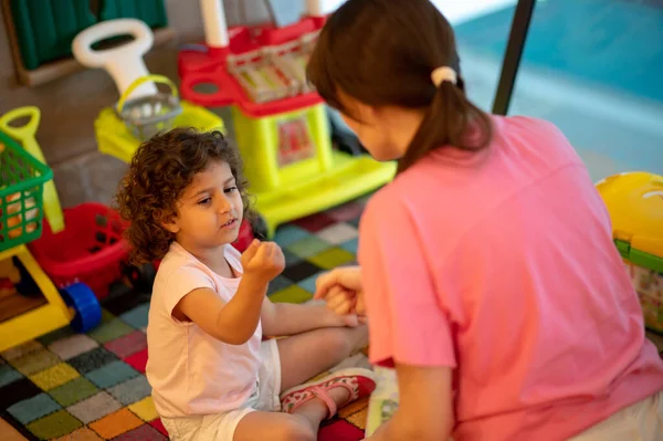 Play room. Young dark-haired woman playing with her kid in a play room