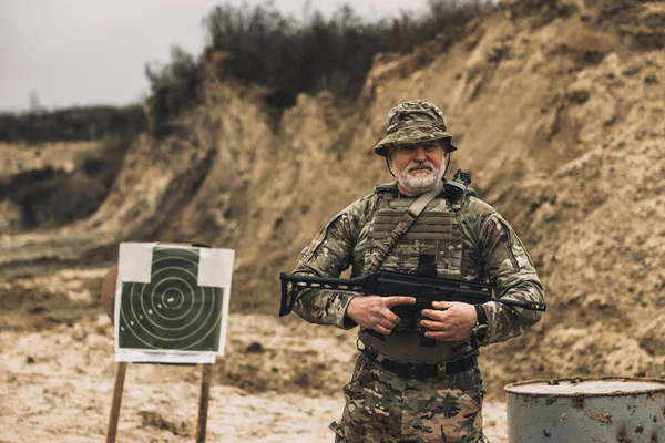 Shooting range. Mature soldier with a rifle in hands on a shooting range
