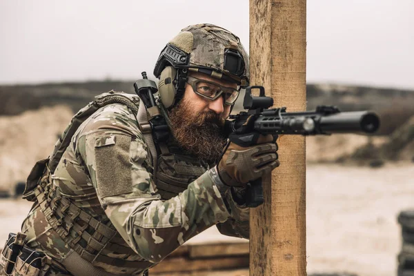 Shooting. Bearded sniper with optical rifle shooting