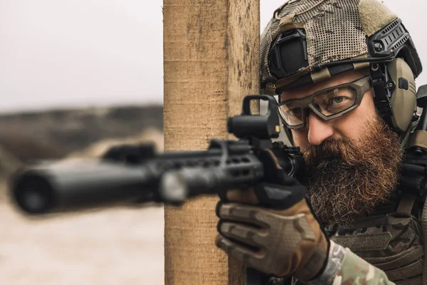 Shooting. Bearded sniper with optical rifle shooting
