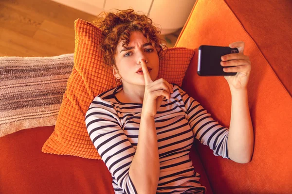 Keep Silence Ginger Cute Girl Lying Sofa Phone Hand Showing — Stockfoto