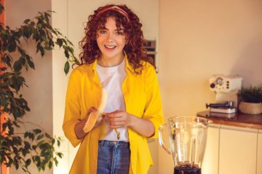 Smoothie preparation. Young girl making smoothie and looking contented