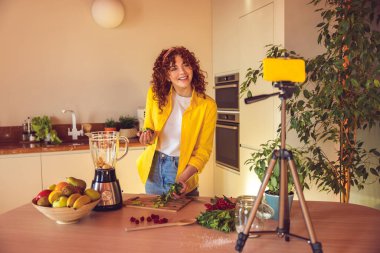 Making smoothie. Happy young girl making smoothie and looking contented