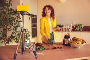 Making smoothie. Happy young girl making smoothie and looking contented