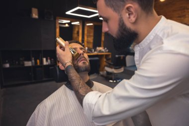 Trimming. Barber in the salon working on the clients beard