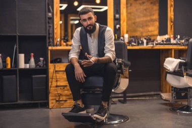 Barber at work. Handsome stylish barber at this working place
