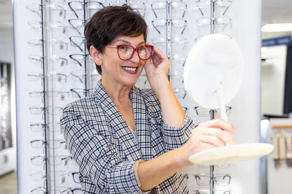 光学店だ 中年良い見ている女性にしようとして眼鏡で光店 — ストック写真