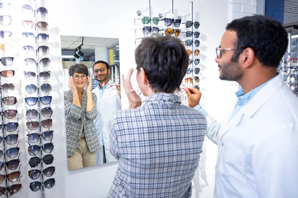 新しいメガネだ 男性観光客は眼鏡を選択する女性を助ける — ストック写真