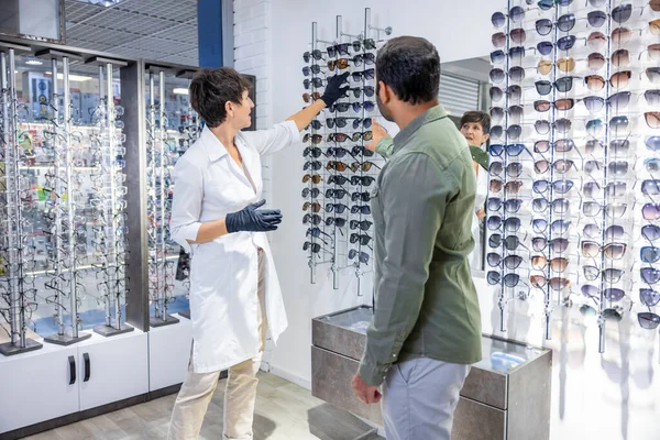 光学店だ 女性の観光客は 訪問者が新しい眼鏡を購入するのを助ける — ストック写真