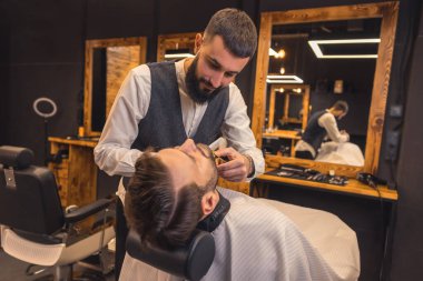 Beard trimming. Barber trimming the clients beard