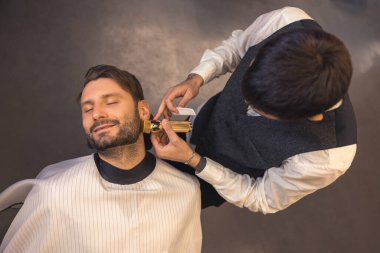 Beard trimming. Barber trimming the clients beard