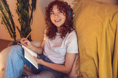 Inspiration. Cute girl writing something in her diary and looking inspired