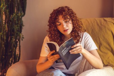 Reading. Ginger curly-haired girl reading a book