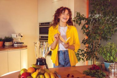 Smoothie preparation. Young girl making smoothie and looking contented