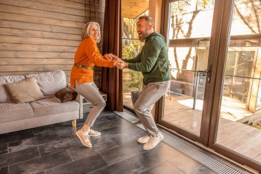 Active couple. Happy couple dancing at home and looking energized and excited