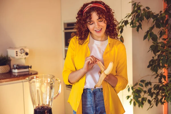 Smoothie preparation. Young girl making smoothie and looking contented