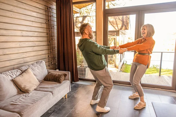 Active couple. Happy couple dancing at home and looking energized and excited