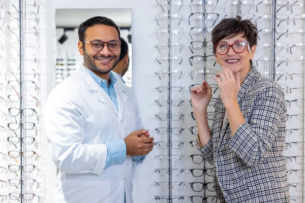 Optical store. Male optometrist helping a woman to choose eyeglasses