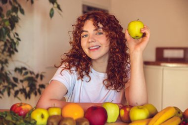 Vegetarian. Ginger girl sitting at the table with many fruits on