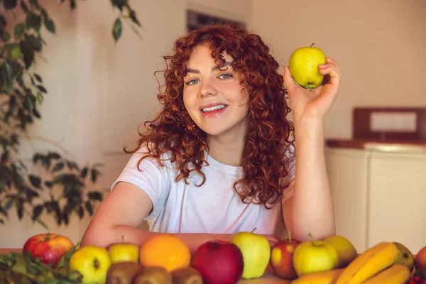 Vegetarian. Ginger girl sitting at the table with many fruits on