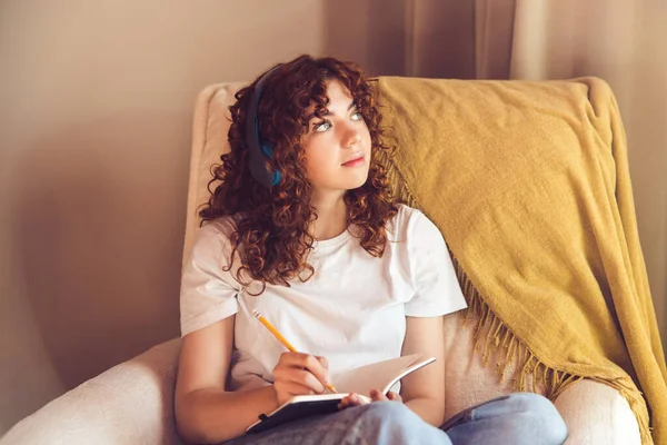 Diary Curly Haired Young Girl Headphones Sitting Armchair Making Notes — Stockfoto