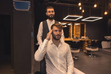 New hairstyle. Young man explaining to the hairdresser how to style his hair