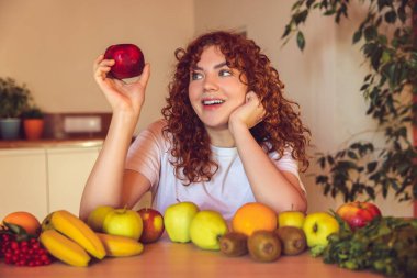 Vegetarian. Ginger girl sitting at the table with many fruits on