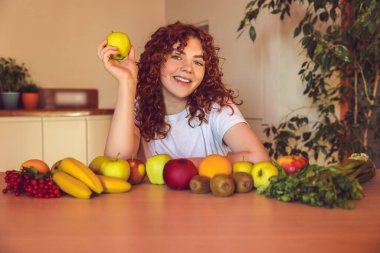 Vegetarian. Ginger girl sitting at the table with many fruits on