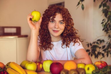 Vegetarian. Ginger girl sitting at the table with many fruits on