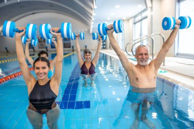 Water aerobics. Young dark-haired coach leading a class of water aerobics