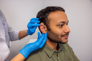 Hearing aid. ENT doctor implementing hearing aid to the patients ear
