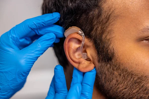 Hearing aid. ENT doctor implementing hearing aid to the patients ear