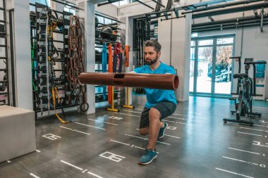 İyi antrenmandı. Sporcu spor salonunda egzersiz yapıyor ve ilgili görünüyor.