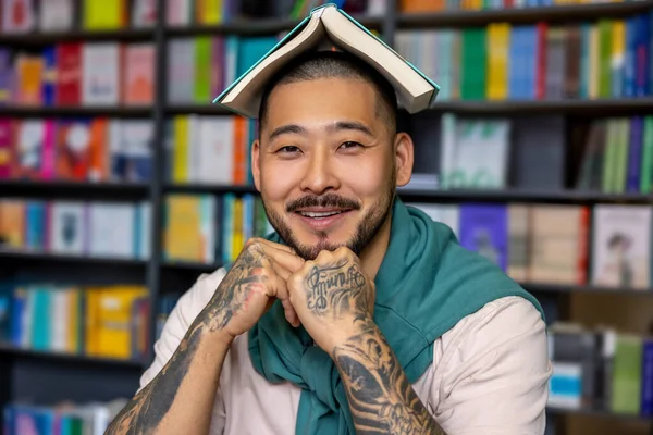 Kütüphanede. Mutlu Asyalı öğrenci kameraya bakıyor.