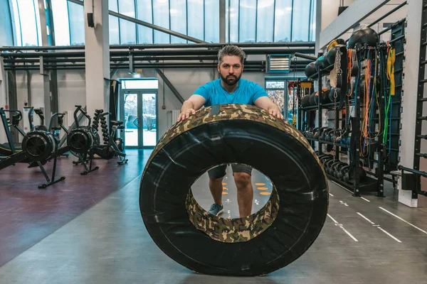 Workout with a training wheel. Athlete rolling a training wheel and looking serious