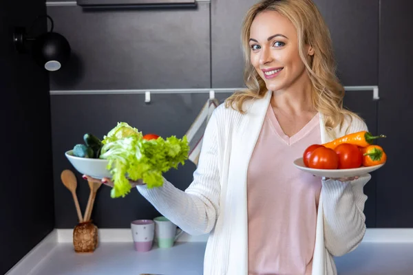 一个快乐的女人拿着两个盘子 手里拿着新鲜蔬菜的蜡像 — 图库照片
