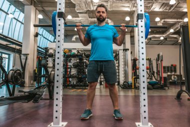 Antrenman yapıyorum. Genç yakışıklı sporcu bar ziliyle egzersiz yapıyor.