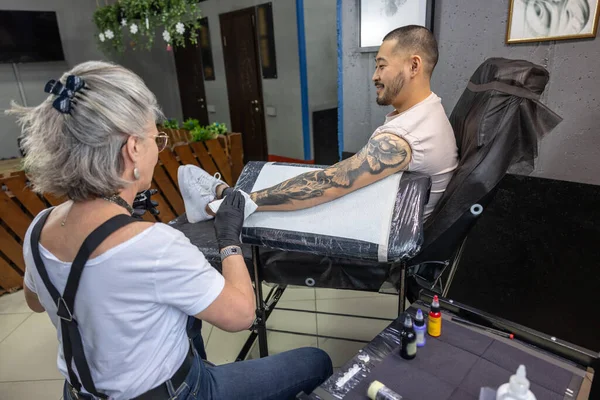 Tattooing process. Tattoo master wotking on a tattoo for the male client