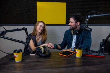 Stüdyoda. Radyo DJ stüdyo konuğuyla konuşuyor ve memnun görünüyor.