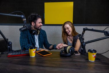 Stüdyoda. Radyo DJ stüdyo konuğuyla konuşuyor ve memnun görünüyor.