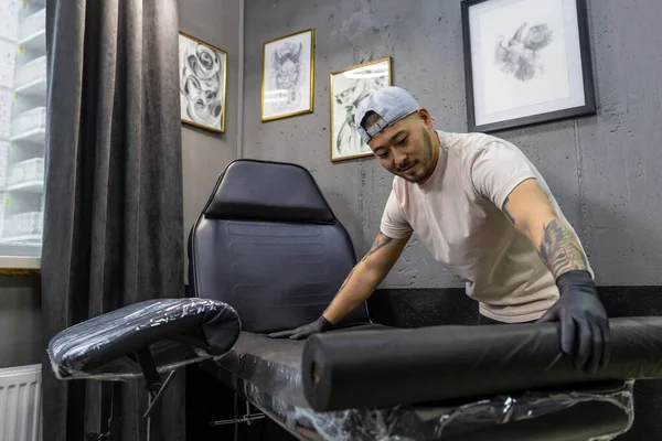 In the tattoo salon. Tattoo master rolling tatto film
