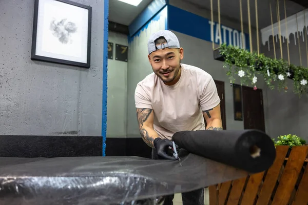 In the tattoo salon. Tattoo master rolling tatto film