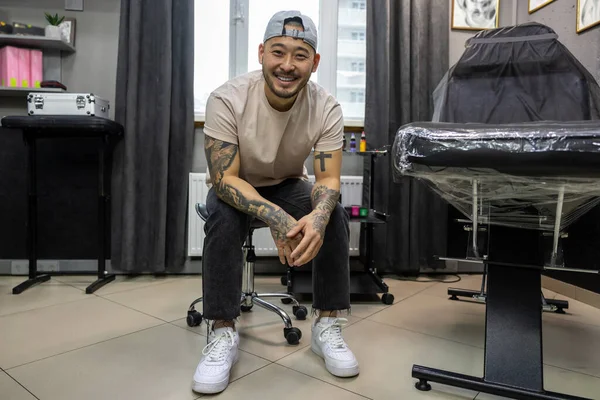 Tattoo salon. Young asian tattoo salon owner feeling good at his workplace