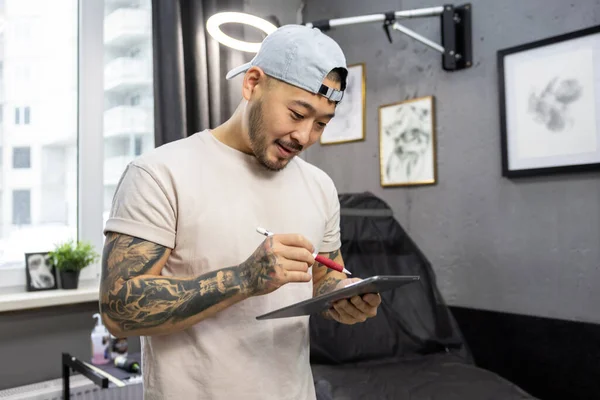 Tattoo salon. Young asian tattoo salon owner feeling good at his workplace
